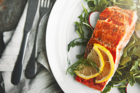 Plate, fish and lemon in restaurant, above and food for health, wellness and nutrition with fine dining. Salmon, dinner and closeup with leaves, vegetables and seafood for diet with pescatarian mealの写真素材