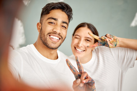 Love, selfie and happy couple with home renovation, diy or house remodel together with peace hands. Smile, profile picture and man with woman, excited and creative for mural, art or paint maintenanceの写真素材