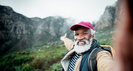 Hiking, selfie and elderly man on mountain for fitness, hobby or wellness in retirement. Exercise, health and portrait of happy senior African person outdoor in nature for adventure or challengeの写真素材