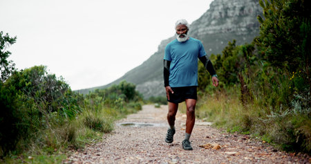 Hip pain, senior black man and injury in nature for fitness, workout or training with accident. Runner, dead leg and elderly sports person on trail hurt with tendinitis, inflammation and arthritisの写真素材