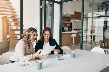 Paperwork, women or analyst in meeting for report, performance results or sales portfolio. Research, business or happy people with documents or project notes for teamwork, trends or planningの写真素材