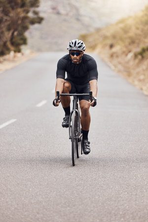 Man, fitness and cyclist with bike on mountain road for workout, exercise or outdoor cardio. Active male person, athlete or biker with helmet on bicycle for cycling, sports or training in natureの写真素材