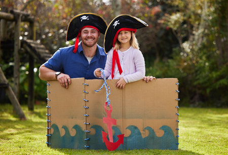 Portrait, pirate and dad with child in box with creativity for playing, pretend games and fun. Family, garden and father with girl for bonding, relax or adventure for fantasy, captain boat or costumeの写真素材