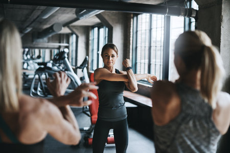 Coach, group and arm fitness in gym for self defense, exercise or muscle workout with strength training. Personal trainer, collaboration or warm up for healthy body challenge, performance or wellnessの写真素材