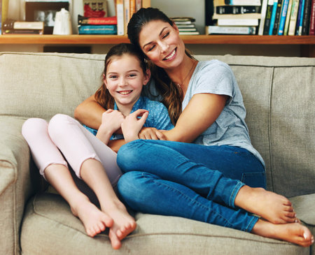 Happy family, woman and daughter in home with hug, affection and couch in bonding for memory as preteen. Cheerful mom, girl and cute for love, support and childhood development on mothers dayの写真素材