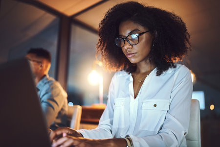 Night, overtime and woman with laptop in office for project information, review or reading IT news. People, developer and feedback with tech for software development, deadline or open source researchの写真素材