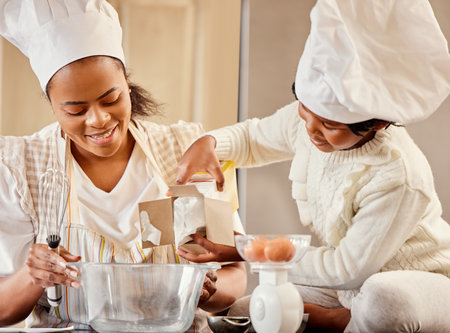 Baking, bowl and black woman in kitchen with child mixing flour, eggs or ingredients for cake in home. Family, cooking and mother teaching girl to bake for development, learning or bonding togetherの写真素材