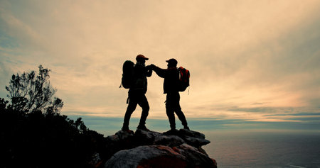 High five, silhouette and success with friends on mountain peak together for fitness, hiking or view of ocean. Celebration, sky and support with hiker people in nature for exercise, hobby or vacationの写真素材