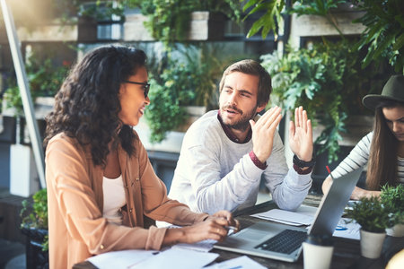 Business people, discussion and laptop in meeting at cafe with technology, paperwork and remote work. Collaboration, data analysis and happy for explaining ideas with strategy, planning and solutionの写真素材