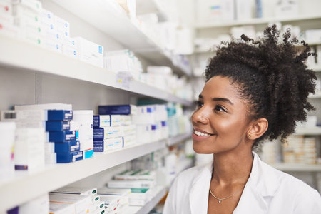 Pharmacy, healthcare and woman at shelf to check medical info, stock inventory or quality assurance. Prescription medicine, pills and African pharmacist with smile, advice and pharmaceutical drugsの写真素材