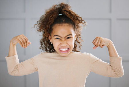 Portrait, girl and strong pose with flexing and muscles in home for growth, development in childhood. Young, female person and confident for health, imagination and milestone for pride or playの写真素材