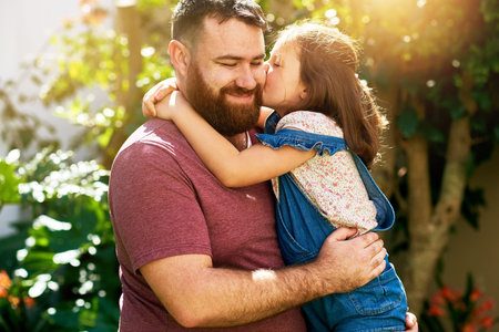 Dad, kid and kiss in backyard with smile, hug and bonding on outdoor weekend with care. love and...