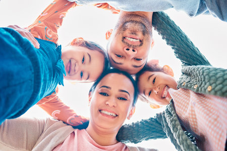 Smile, huddle and portrait of family with support, blue sky and bonding together in nature. Low angle, face and parents with man and woman for childhood, solidarity and fun or joy with embraceの写真素材