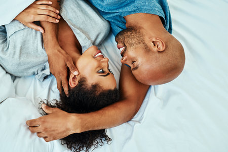 Cuddle, happy and above of couple in bed in morning for bonding, relationship and love. Marriage, home and man and woman in bedroom embrace for comfort, resting and affection for trust and careの写真素材