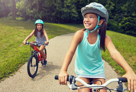 Outdoor, nature and children with bicycle for riding, learning and playing together with helmet for safety. Park, path and happy girls for cycling, bike activity and coordination with balanceの写真素材