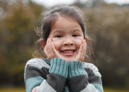 Asian portrait, child and girl in nature for outdoor playing with growth, blurred background and relax in garden. Youth, kid and happy for fun adventure with development, smile and park in Singaporeの写真素材