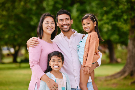 Portrait, happy and family with love outdoor for bonding, care and embrace of travel adventure at park. Smile, Asian people and parents with kids for support and fun holiday together for childhoodの写真素材