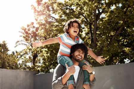 Happy father, child and bonding or carry on shoulders at backyard for love, freedom or holiday together at home. Dad with son, kid or little boy for fun flying game or enjoying weekend in natureの写真素材