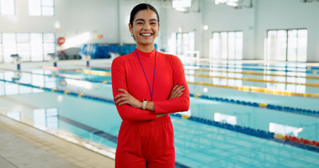 Smile, crossed arms and portrait of swimming instructor at indoor pool for lesson, workout or training. Happy, confident and woman coach with pride for competition practice at aquatic center.の写真素材