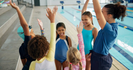 Swimming pool, lesson and teacher with kids with high five for learning, practice and training. Teamwork, celebrate and swimmer instructor with children for exercise, fitness and water sports classの写真素材