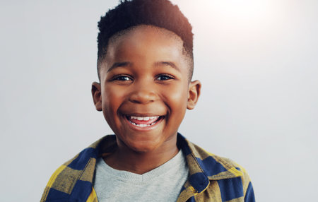 Portrait, happy and black child in studio for fashion, excited and summer fun. Young kid, smile and face on white background for positive energy, passport or junior school profile update in Nigeriaの写真素材