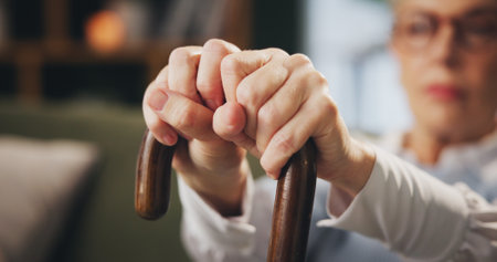 Walking stick, hands and senior woman with disability at home, arthritis and depression in retirement. House, elderly lady and thinking with wooden cane for balance, vertigo disease and osteoporosisの写真素材