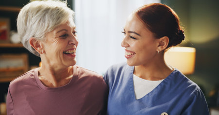 Healthcare, smile and nurse with senior woman in assisted living for medical consultation. Happy, bonding and caregiver hug elderly female patient for kindness at wellness checkup in retirement home.の写真素材