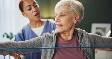 Women, physiotherapist and senior patient with elastic rope for rehabilitation, support and...