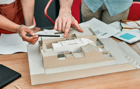 Hands, people and model of building at architecture agency with review, point and planning with teamwork. Engineer, partnership and 3D construction with blueprint, check and inspection for propertyの写真素材