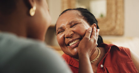 Mature, mom and daughter with hand on face for love, gratitude and affection or emotional connection. Black family, woman and happy mother with embrace in home, bonding and together with support.の写真素材
