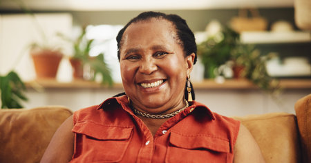 Happy, senior and black woman with portrait on sofa for relax in home for retirement, wellness and comfort. Elderly female person, smile and lounge in living room of house with peace on pension.の写真素材