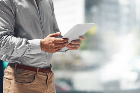 Businessman, hands and browsing with tablet for news, research or onlline connection at office. Closeup of male person, employee or analyst on technology app, development or mockup space at workplaceの写真素材
