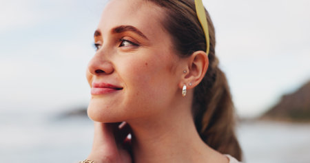 Happy woman, thinking and beach with vision for freedom, holiday or outdoor weekend in nature. Face of young female person with smile in wonder or thought for vacation or sightseeing by ocean coastの写真素材