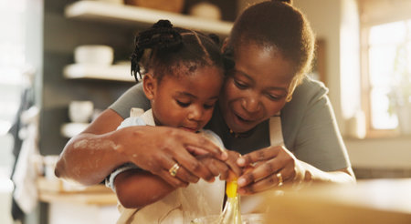 Education, child and black woman in kitchen for baking, recipe or help cracking egg at home. Girl, development and mother at counter for growth, learning or fun activity for making dough for cookiesの写真素材