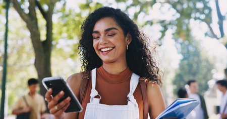Campus, park or happy woman with phone in university for learning application or higher education. Social media text, smile or student on internet for academic registration or scholarship resultsの写真素材