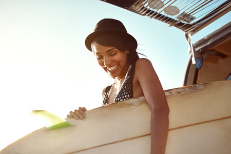 Woman, surfboard and happy by car for road trip in summer for beach, adventure and outdoor on holiday in nature. Person, surfer and smile by vehicle for transport in sunshine for vacation in Brazilの写真素材