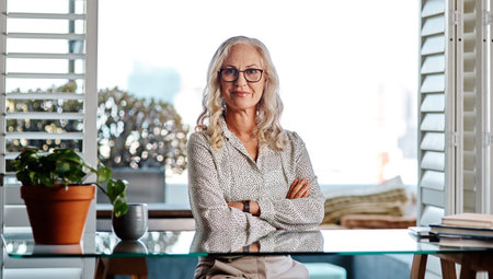 Portrait, mature woman and creative in office, publisher and professional in publishing agency and glasses. Confident, proud and arms crossed for planning for budget, ambitious and wise in businessの写真素材