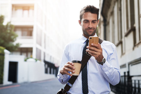 Coffee, phone and business man in city for reading email, text or message on commute outdoor. Mobile, drink and worker in town online for info, research or salesman check agenda app to plan scheduleの写真素材