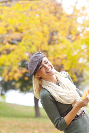 Fashion, happy and woman with leaf in nature for Autumn weather on holiday, getaway or vacation....