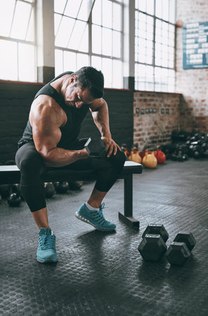 Dumbbell, exercise and weight training with bodybuilder man on bench in gym for challenge or...