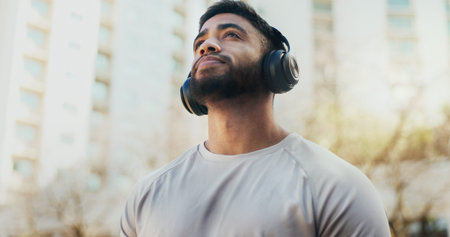 Fitness, headphones and man in city for running, workout or training for race endurance or stamina....