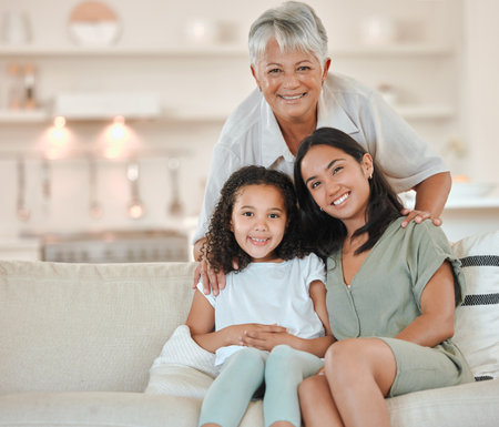 Portrait of grandmother, mom and child on sofa for bonding, love or relax in living room. Family generation, happy home and grandma, mother and girl on couch with smile, hug or embrace in living roomの写真素材