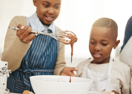 Children, baking and whisk with chocolate in bowl for mixture, ingredients or learning with help in...