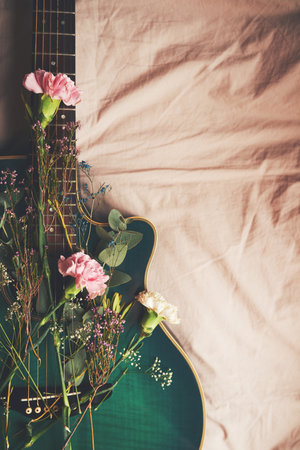Art, plants and guitar with flowers in home, green and creative with nature in bedroom and above. Bed, music and equipment with floral in house, instrument and entertainment for performance or talentの写真素材