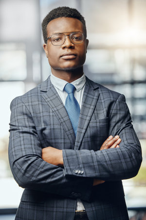 Black man, portrait and lawyer with glasses in confidence for legal rights, professional firm or agency at office. Serious African advocate, male person or young attorney with arms crossed for lawの写真素材