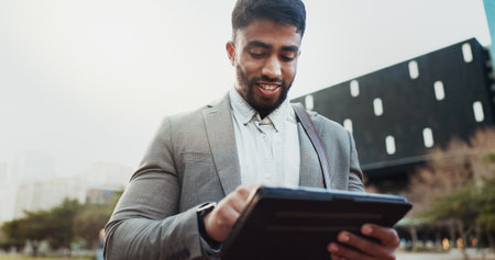 Business, typing and man with tablet in city, smile or internet for research, website info or connection. New York, attorney or lawyer with tech, digital app or email notification with social networkの写真素材