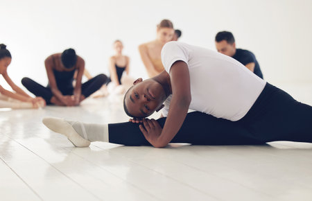 Boy, ballerina and split for stretching in class with training, muscle and start lesson at dance school. Person, dancer and warm up in studio, floor and academy for legs, art and ready for concertの写真素材