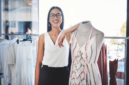 Happy woman, portrait and fashion designer with mannequin in confidence for small business at boutique. Young, female person or tailor with smile or measuring tape for garment or clothing productionの写真素材