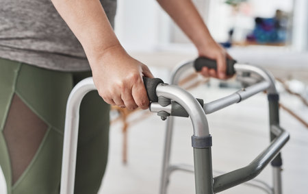 Physical therapy, hands and walker for exercise, wellness and help in gym, clinic or session. Person with a disability, injury and physiotherapy for fitness, muscle recovery and rehabilitation centerの写真素材