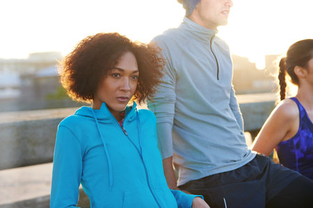 Woman, runner group and break at sunrise on bridge, vision and wellness in morning with diversity....